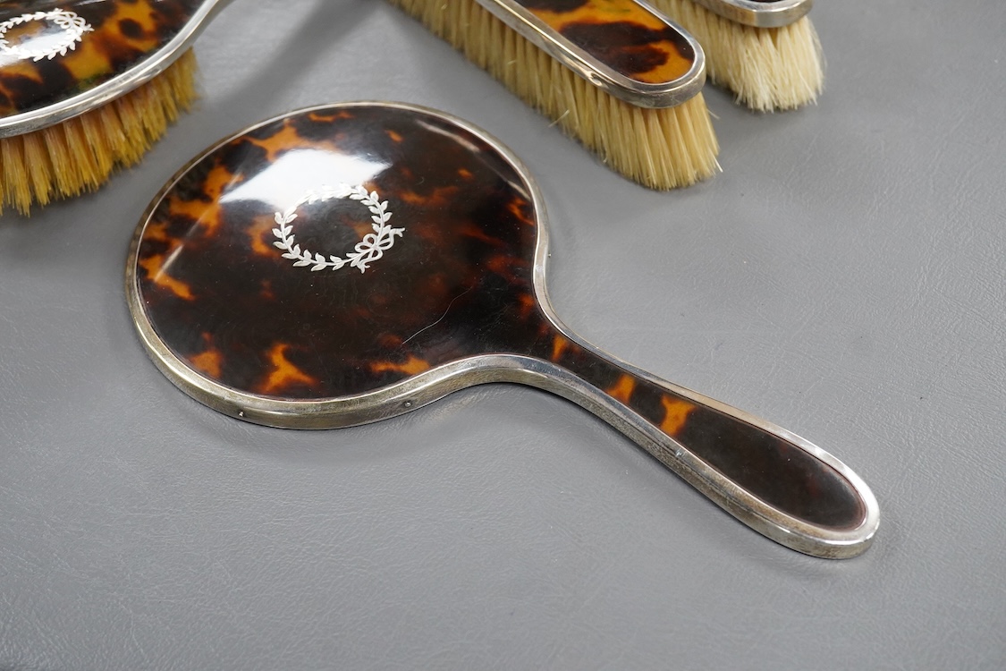 A matched George V silver and tortoiseshell mounted four piece mirror and brush set, Birmingham, 1927/8/9, mirror 22.7cm.